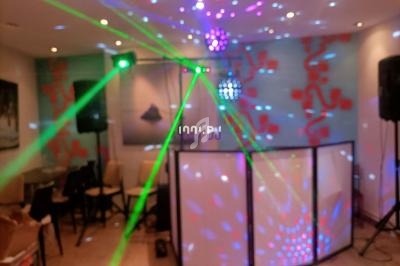Je ne sais pas qui est sur cette image, mais elle montre une salle avec des jeux de lumières colorées et un équipement de DJ.