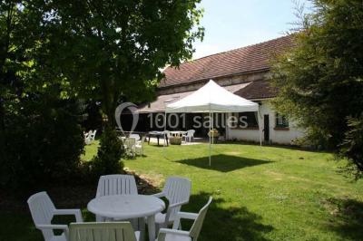 Chaises blanches empilées et disposées sur une pelouse entourée d'arbres par une journée ensoleillée.