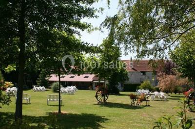 Chaises blanches empilées et disposées sur une pelouse entourée d'arbres par une journée ensoleillée.