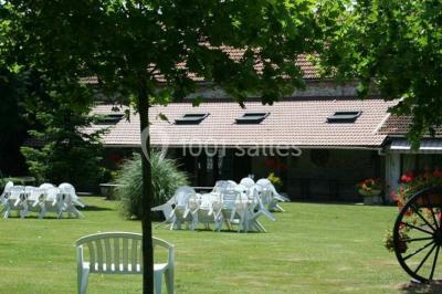 Chaises blanches empilées et disposées sur une pelouse entourée d'arbres par une journée ensoleillée.