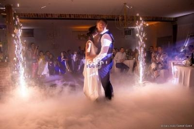 Un couple danse au milieu d'une piste entourée de fumée et d'étincelles, sous le regard des invités.