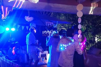 Groupe de personnes dans une ambiance festive nocturne avec éclairages colorés et décorations suspendues.