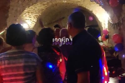 Groupe de personnes dans une cave voûtée éclairée, décorée de ballons et lumières colorées, lors d'une fête.