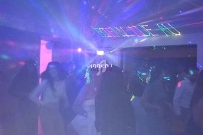 Des personnes dansent dans une salle sombre éclairée par des lumières colorées et des effets laser.