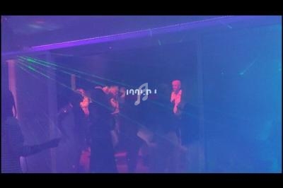 Des personnes dansent dans une ambiance sombre avec des lumières colorées et des effets de laser.