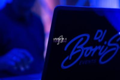 Un DJ mixant sur un ordinateur portable dans une ambiance lumineuse bleutée.