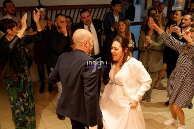 Un couple danse au centre d'une piste entouré d'invités applaudissant dans une ambiance festive.