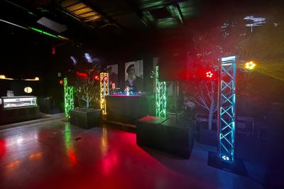 Scène éclairée avec projecteurs colorés et écran central affichant des graphismes lumineux dans une ambiance sombre.