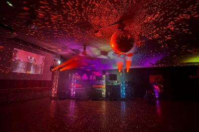 Scène éclairée avec projecteurs colorés et écran central affichant des graphismes lumineux dans une ambiance sombre.