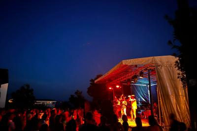 Scène éclairée avec projecteurs colorés et écran central affichant des graphismes lumineux dans une ambiance sombre.