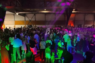 Groupe de personnes dansant et socialisant dans une grande salle éclairée par des lumières colorées.