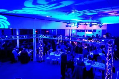 Salle de réception éclairée en bleu avec des invités assis à des tables rondes lors d'un événement en soirée.