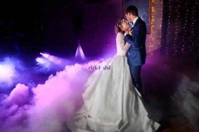 Un couple danse dans une ambiance romantique avec éclairages colorés et fumée au sol.