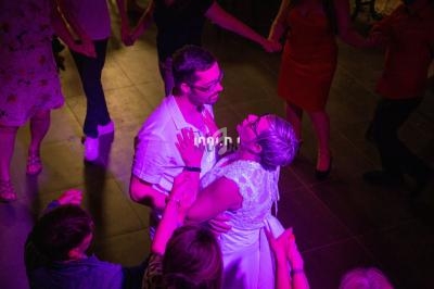 Un couple danse au centre d'une piste entouré de personnes sous un éclairage rose.