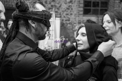 Un homme ajuste un bandeau sur la tête d'une femme lors d'une activité en groupe dans un espace intérieur.