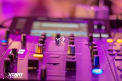 Table de mixage avec des boutons et curseurs éclairés, utilisée dans un environnement lumineux et coloré.