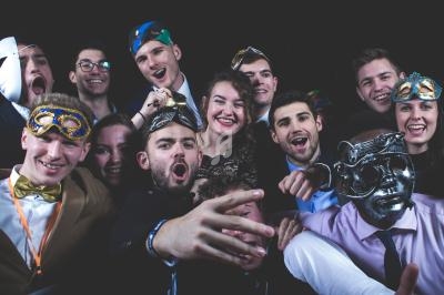 Un groupe de personnes souriantes portant des masques colorés, posant pour une photo dans un cadre festif.