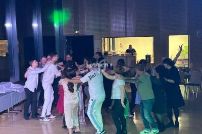 Un groupe de personnes dansant en cercle dans une salle éclairée, avec un bar visible en arrière-plan.