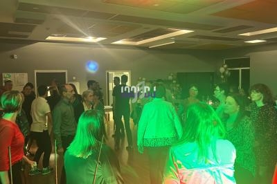 Groupe de personnes debout dans une salle éclairée, discutant et socialisant lors d'un événement en soirée.