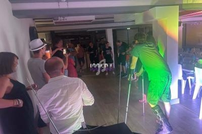 Des personnes participent à une soirée dansante dans une salle éclairée par des lumières colorées.