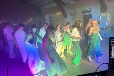 Des personnes dansent en groupe dans une salle éclairée par des lumières colorées, ambiance festive et décontractée.