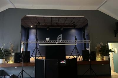 Scène intérieure avec éclairage tamisé, équipement audio et décoration végétale sur les côtés.