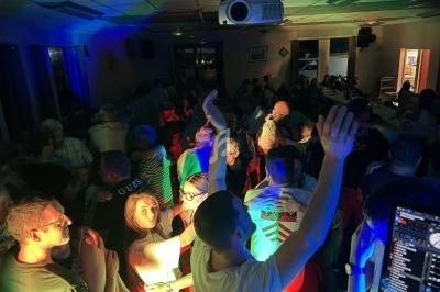 Groupe de personnes dansant et socialisant dans une salle éclairée par des lumières colorées.
