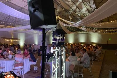 Salle de réception décorée avec des guirlandes lumineuses, des invités assis à des tables rondes sous un éclairage tamisé.