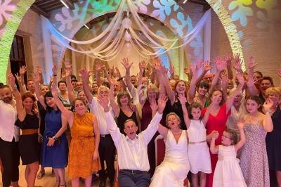Groupe de personnes souriantes levant les bras dans une salle décorée de voilages et de lumières colorées.