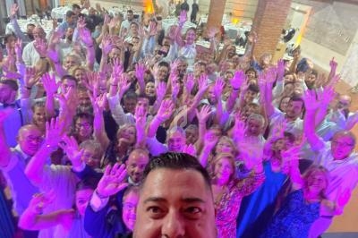 Un groupe de personnes souriantes levant les mains lors d'un événement dans une salle éclairée.