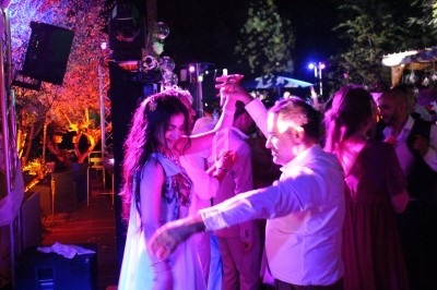 Un couple danse sous des lumières colorées lors d'une fête en plein air, entouré d'autres invités.