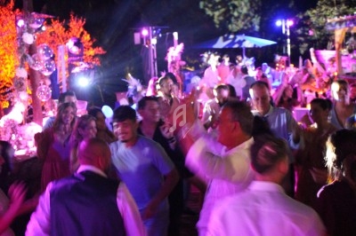 Groupe de personnes dansant lors d'une fête en soirée, éclairée par des lumières colorées et une ambiance festive.