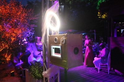 Boîtier photo avec éclairage circulaire installé en extérieur lors d'un événement nocturne avec invités en arrière-plan.