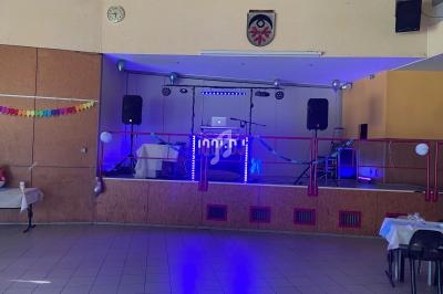 Scène décorée avec des lumières bleues, des enceintes et un ordinateur portable, prête pour un événement festif.