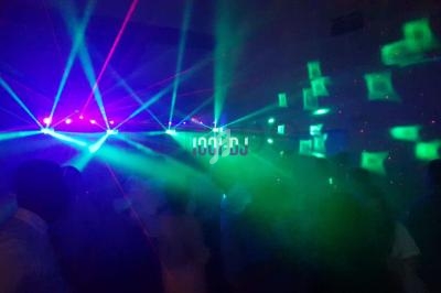 Jeu de lumières colorées avec lasers et fumée lors d'une soirée dansante en intérieur.