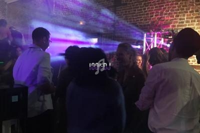 Groupe de personnes dansant dans une salle avec des lumières colorées et un mur en briques apparentes.