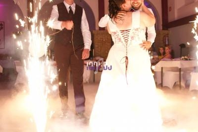 Un couple de mariés danse entouré d'effets pyrotechniques dans une salle décorée.
