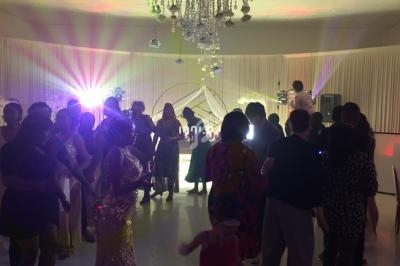 Groupe de personnes dans une salle de réception éclairée par des lumières colorées, avec un lustre au plafond.