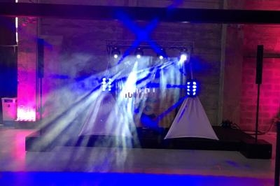 Jeux de lumières colorées sur une scène dans une salle avec murs en béton et ambiance tamisée.