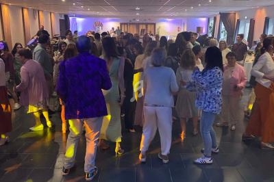 Des personnes dansent dans une salle éclairée, entourées de convives lors d’un événement festif.