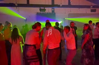 Des personnes dansent dans une salle sombre éclairée par des faisceaux lumineux colorés.