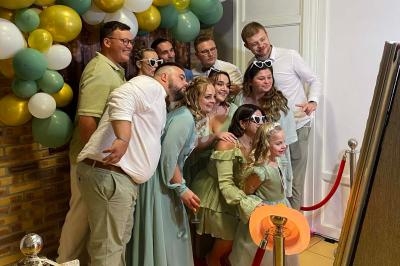 Un groupe de personnes posant devant un miroir, entouré de ballons décoratifs et d'une corde rouge.