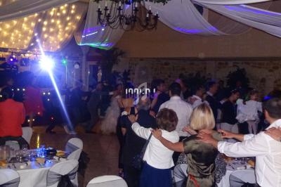 Des invités dansent en cercle sous un plafond décoré de voilages et de lumières dans une salle de réception.