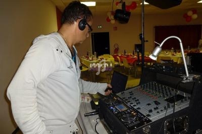 Homme portant un casque audio, utilisant une table de mixage dans une salle décorée pour un événement.