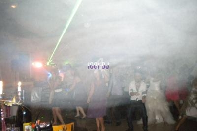 Groupe de personnes dansant dans une ambiance festive avec jeux de lumière et fumée.