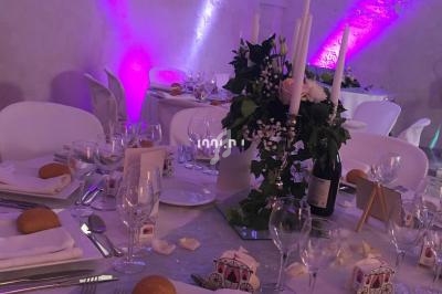 Table de réception décorée avec des bougies, fleurs blanches et violettes, serviettes pliées et petits pains.
