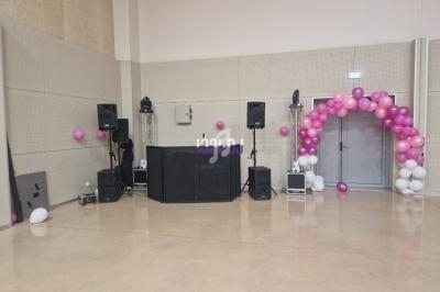 Installation de matériel de sonorisation avec des ballons roses et blancs décorant une arche près d'une porte.