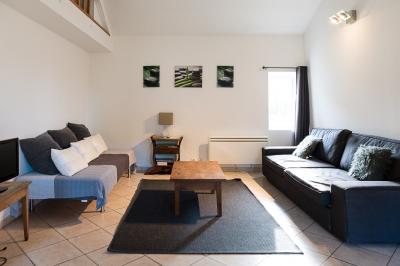 Pelouse verdoyante entourée de grands arbres sous un ciel partiellement nuageux.