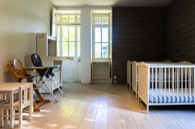 Pelouse verdoyante entourée de grands arbres sous un ciel partiellement nuageux.