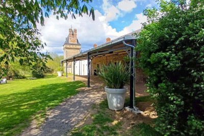 Pelouse verdoyante entourée de grands arbres sous un ciel partiellement nuageux.